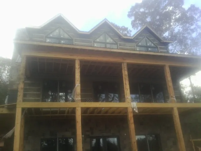 Dormers and porch framing on a large log home under construction — Roof Coating work by our crew in Ferdinand